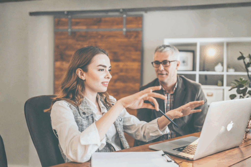 A mentor and mentee in a mentoring session discussing ideas at a desk with a laptop, representing professional support and growth.